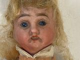 a close up of a doll with blonde hair and blue eyes