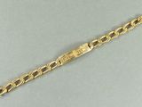 gros plan d'un bracelet en or sur une surface grise