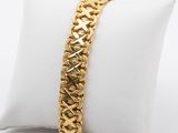 a close up of a gold bracelet on a white pillow