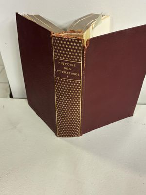 un vieux livre posé sur une table blanche à côté d'un mur blanc
