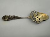 a silver spoon with a leaf design on it sitting on top of a table
