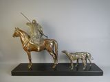 statue représentant un homme à cheval accompagné d'un chien, posée sur un socle noir