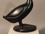 statue of a black bird on a marble base on a gray background
