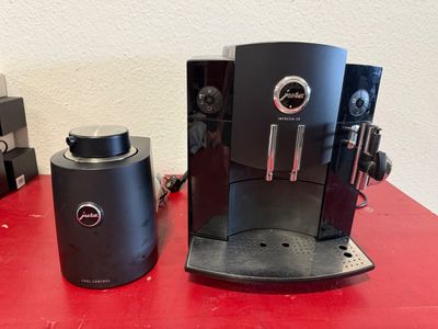 two coffee machines sitting on a red table next to each other