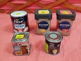 quatre boîtes de conserve sont posées sur un lit recouvert d'une couverture rose