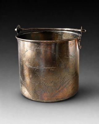 une vieille casserole en argent avec une poignée, sur fond noir
