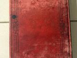 an old red book sitting on top of a tiled floor