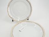 two white plates with gold trims and a gold rim