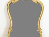 un miroir à cadre doré posé sur un parquet
