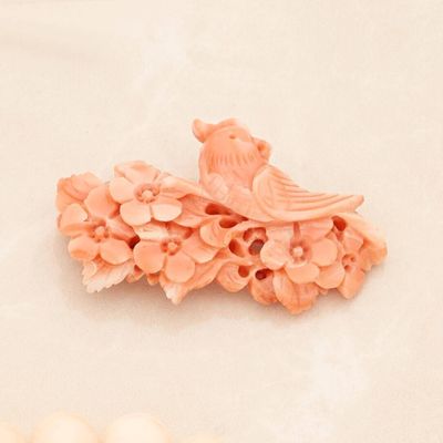 a bird sitting on top of a flowered brooch