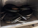 pots and pans are stacked on a metal shelf in a kitchen
