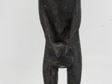 statue of a man sitting on a stool with his hands on his knees