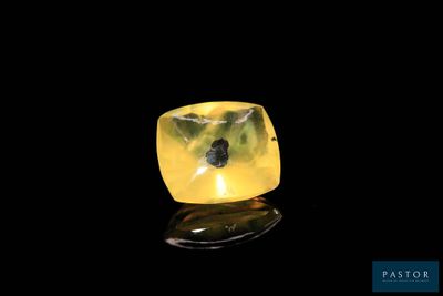 a close up of a yellow diamond on a black surface