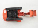 a red toy tractor with black wheels on a white surface