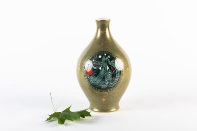 un petit vase orné d'un dessin, à côté d'une feuille