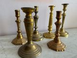four brass candlesticks sitting on a marble table