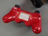 a red game controller sitting on a table next to a charger