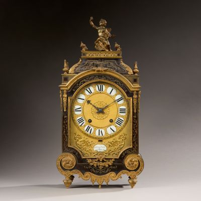 a gold clock with roman numerals on the face