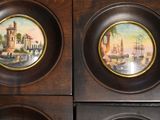 three plates with paintings of boats on them on a wooden surface