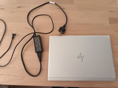 un ordinateur portable et un chargeur posés sur une table en bois