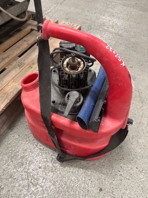 a red blower sitting on the ground next to a pallet