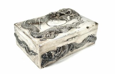 a silver box with a dragon on it on a white surface