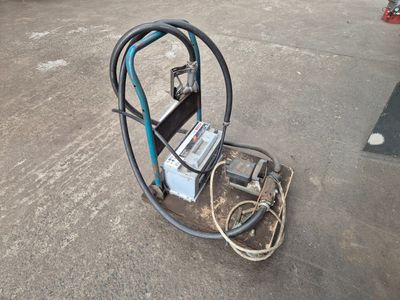 une machine posée à même le sol, à côté d'un tuyau d'arrosage