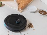 a robot that is sitting on the floor next to bowls of food