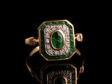 gros plan d'une bague en or avec une pierre verte et des diamants