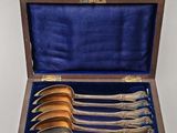 six spoons in a wooden box with a blue velvet lining