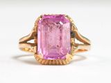a close up of a pink stone ring on a white surface