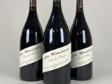 trois bouteilles de vin rouge sont alignées sur une surface blanche