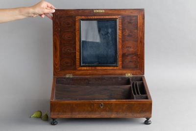 une personne tenant une petite boîte en bois contenant un miroir