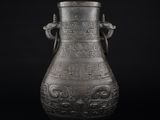 un vieux vase en métal orné de sculptures sur fond noir