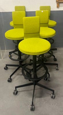 Des chaises et des tabourets jaunes sont alignés contre un mur