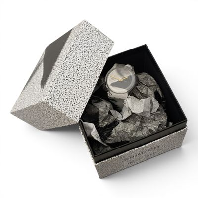une boîte avec une montre à l'intérieur sur une surface blanche