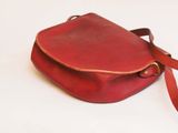 red leather purse with strap on a white background