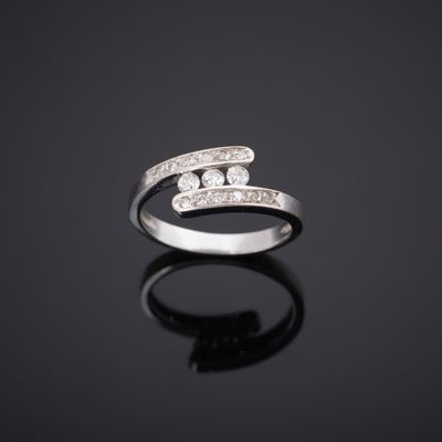 une bague en or blanc et diamants posée sur une surface noire