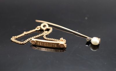 une broche en perle et en or posée sur un fond noir