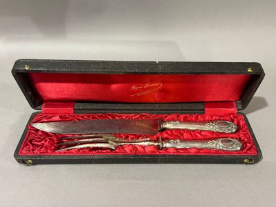 un service d'argenterie dans un coffret rouge posé sur une table