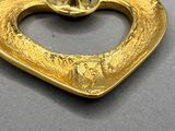 une broche en forme de cœur dorée sur un fond gris