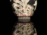 a black and white vase with a gold design on it
