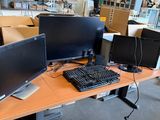 deux écrans et un clavier posés sur un bureau dans un entrepôt