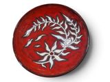 a red plate with a design on it on a white surface