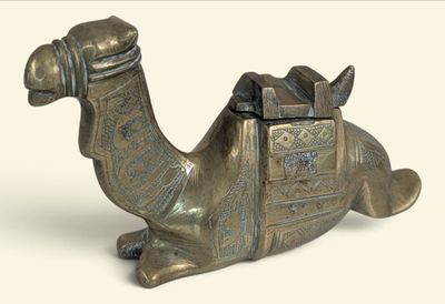 une statue en bronze représentant un chameau avec une selle sur le dos