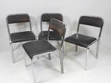 three black chairs and a stool sit in a row against a white wall