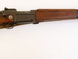 un vieux fusil avec un canon en bois sur une surface blanche