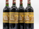quatre bouteilles de vin sont alignées sur une surface blanche