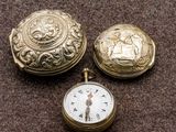 deux montres de poche en or et une montre de poche en or posée sur une surface marron