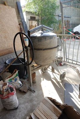 un grand pot en ciment posé par terre à côté d'un tas de bois